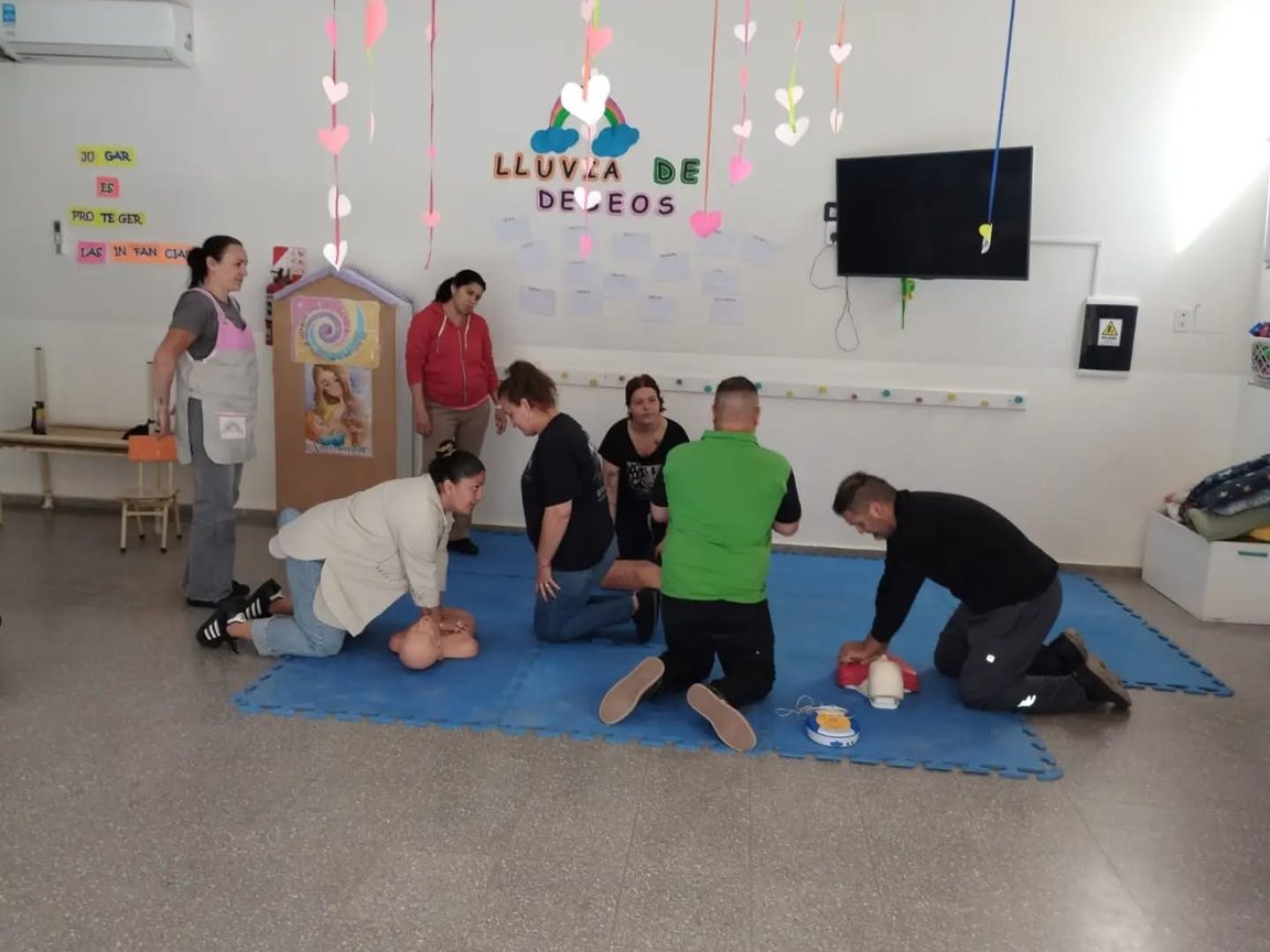 Familias y educadoras practican la reanimación con muñecos durante la capacitación en el CDI