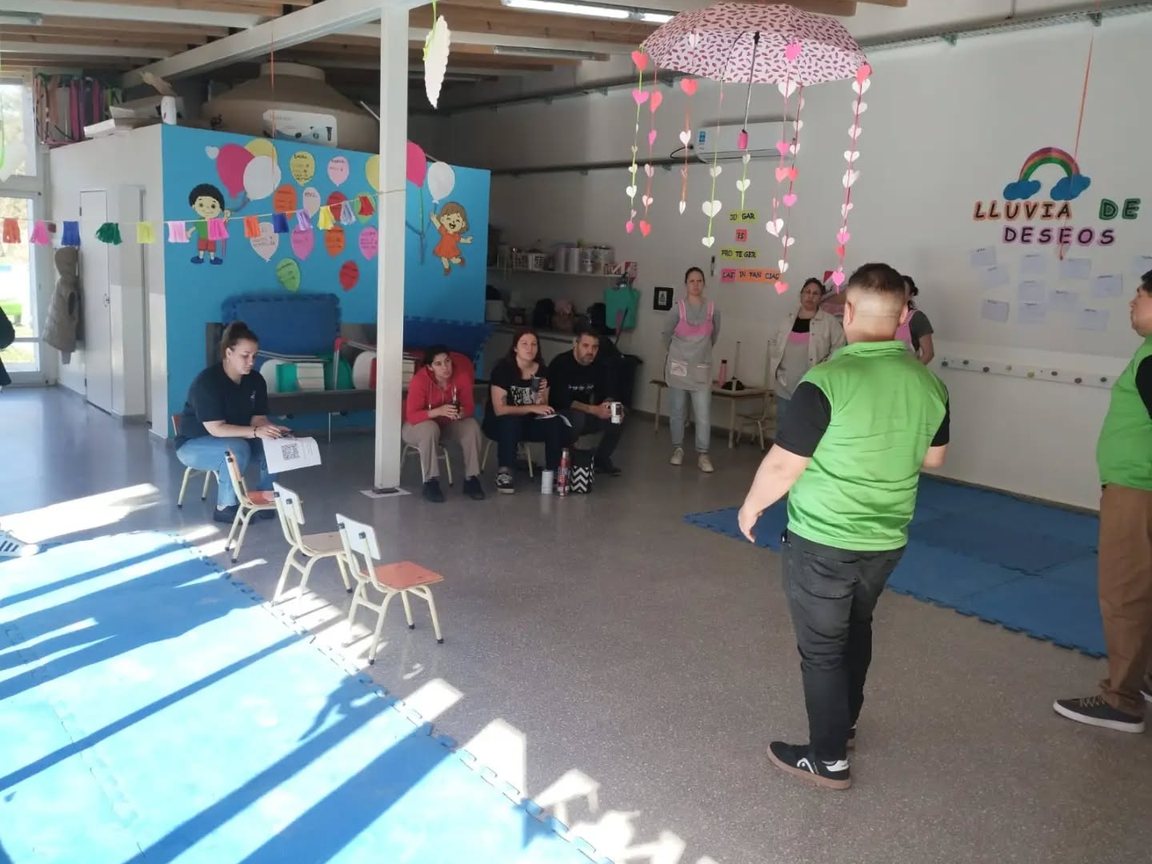 Familias y educadoras sentadas escuchan a los instructores en el salón del CDI